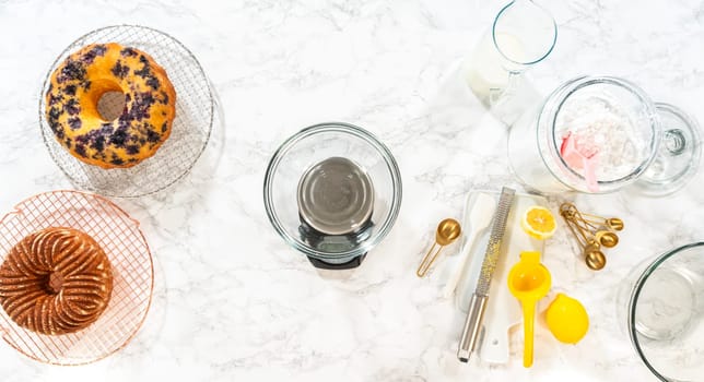 Flat lay. Skillfully combine ingredients using a hand mixer to prepare a rich, smooth cream cheese buttercream frosting, which is perfect for adorning the bundt cake.