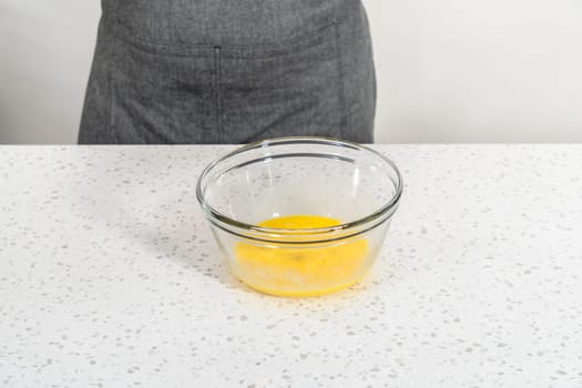 Mixing wet ingredients in a small glass mixing bowl to bake a simple vanilla bundt cake.