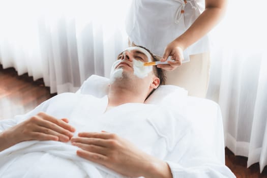 Serene ambiance of spa salon, man customer indulges in rejuvenating with luxurious face cream massage with modern daylight. Facial skin treatment and beauty care concept. Quiescent