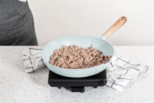 Browning ground turkey on a nonstick frying pan to bake turkey empanadas.