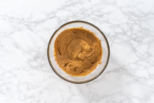 Mixing ingredients in a large glass mixing bowl to bake gingerbread cupcakes.