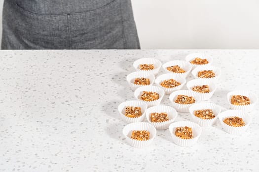 Homemade pumpkin spice fudge square pieces in white paper cupcake liners on a kitchen counter.