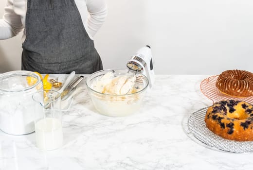 Skillfully combine ingredients using a hand mixer to prepare a rich, smooth cream cheese buttercream frosting, which is perfect for adorning the bundt cake.