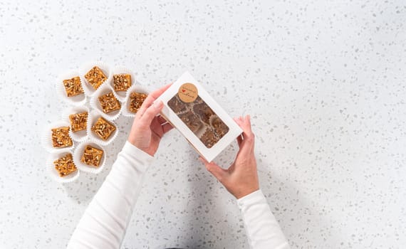 Flat lay. Packaging homemade pumpkin spice fudge with pecans into a white paper gift box.