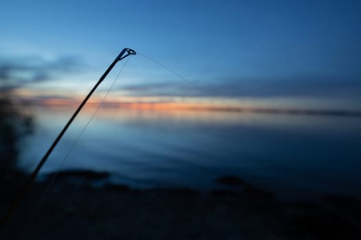 fishing rod with a lake in the background during sunset