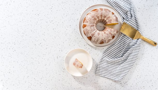 Flat lay. Sliced vanilla bundt cake with a vanilla glaze on a white plate.