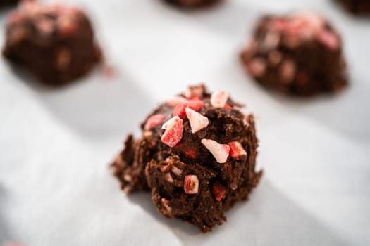 Scooping chocolate cookie dough with dough scoop to bake chocolate cookies with peppermint chips.