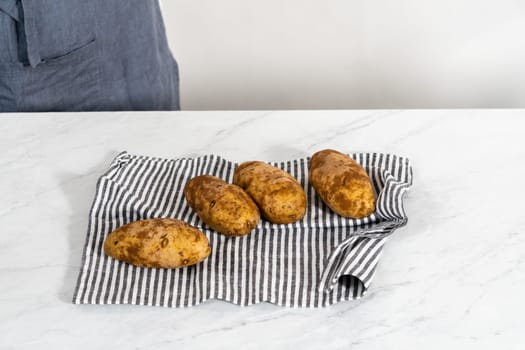 Pressure Cooker Baked Potatoes. Poking raw potatoes with a fork to prepare baked potatoes.