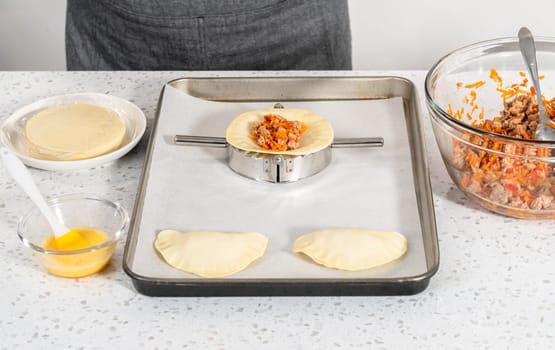 Flat lay. Filling empanada dough with turkey filling to make turkey empanadas.