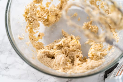 Mixing ingredients with a hand mixer to bake eggnog cookies with a chocolate gingerbread man.