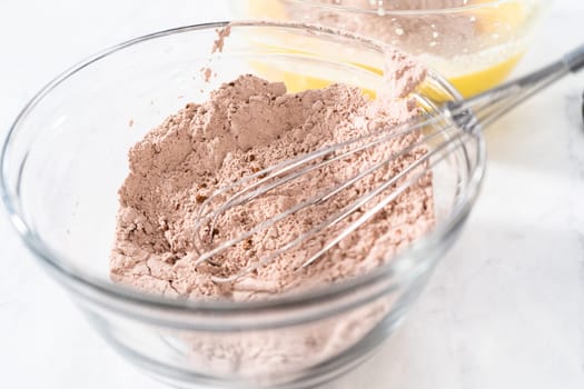 Mixing ingredients in a large glass mixing bowl to bake red velvet bundt cake with cream cheese glaze.