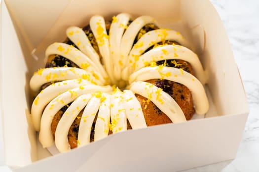 The freshly baked bundt cakes are carefully nestled into white paper boxes, preparing them for secure transportation while maintaining their delectable appearance.