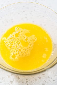 Mixing wet ingredients in a small glass mixing bowl to bake a simple vanilla bundt cake.