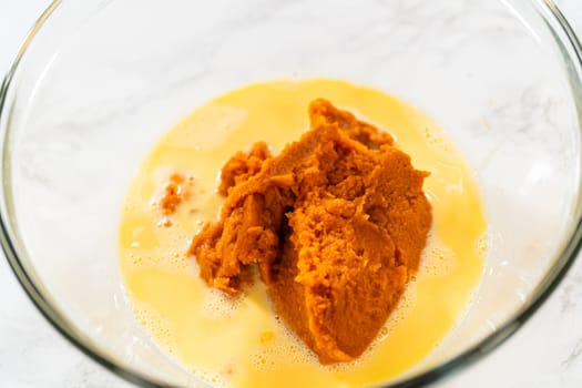 A close-up view of expertly blended ingredients in a large mixing bowl for a mouthwatering homemade pumpkin bundt cake.