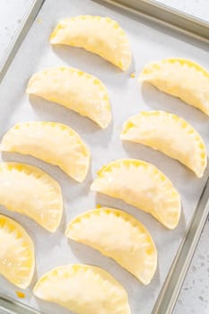 Brushing uncooked turkey empanadas with egg wash.