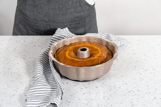 Cooling freshly baked simple vanilla bundt cake on a kitchen counter.