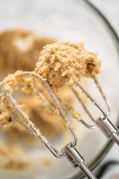 Mixing ingredients in a large glass mixing bowl to bake gingerbread cupcakes.