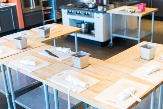 Tables prepared with white cutting boards and aprons for cooking class.
