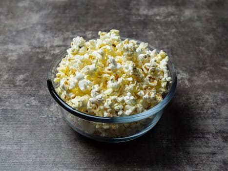 popcorn in a glass bowl on a wooden table