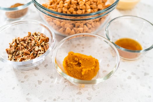 Measured ingredients in glass mixing bowls to prepare pumpkin spice fudge with pecans.