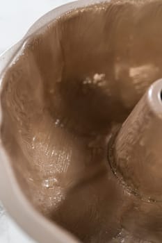 Greasing a bundt cake pan with vegetable shortening, preparing to bake a delightful homemade pumpkin bundt cake.