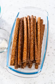 Measured ingredients in glass mixing bowls to make Halloween chocolate-covered pretzel rods.