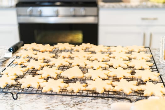 Letting delightful snowflake-shaped sugar cookies cool on a rack, preparing them for festive Christmas gifts.