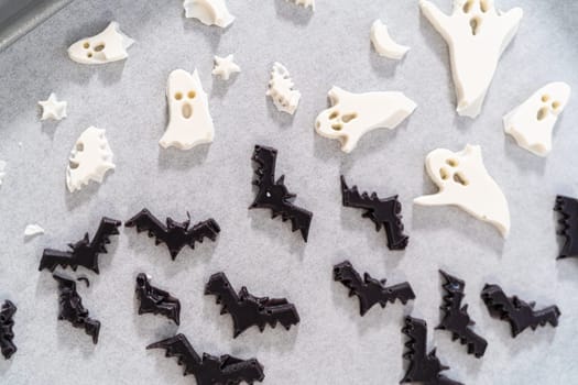 Filling Halloween silicone mold with melted chocolate to make chocolate decor for pretzels.