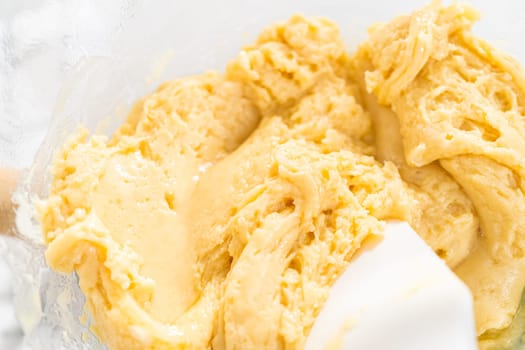 Melting white chocolate chips and other ingredients in a glass mixing bowl over boiling water to prepare candy cane fudge.