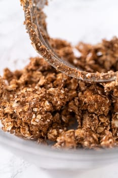 Mixing ingredients in a large glass mixing bowl to prepare cinnamon crumb topping.