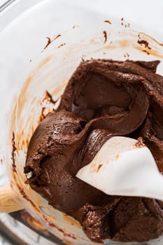 Melting white chocolate chips and other ingredients in a glass mixing bowl over boiling water to prepare candy cane fudge.