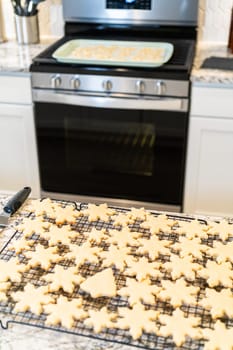 Letting delightful snowflake-shaped sugar cookies cool on a rack, preparing them for festive Christmas gifts.