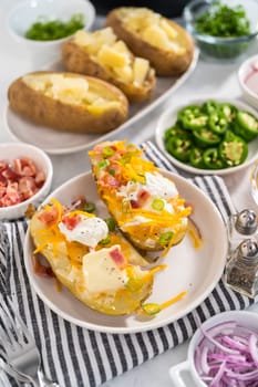 Pressure Cooker Baked Potatoes. Garnished large baked potatoes with butter, sour cream, cheese, and bacon bits on a white plate.