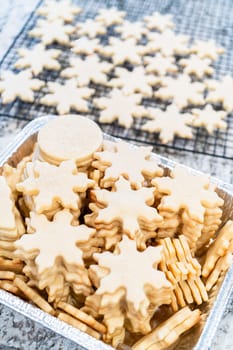 Carefully stacking the beautifully crafted snowflake-shaped sugar cookies into a foil pan, ready for freezing as delightful Christmas treats.