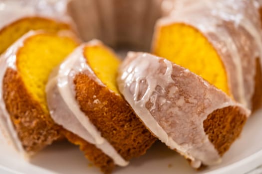 Sliced vanilla bundt cake with a white glaze on a white plate.