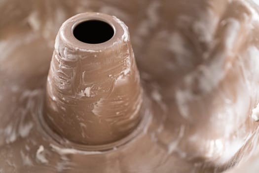 Greasing metal bundt cake pan to bake a simple vanilla bundt cake.