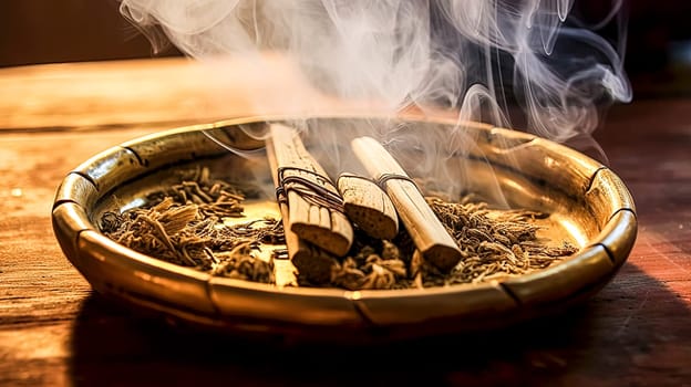 A hand is reaching into a bowl of incense sticks. The incense sticks are burning and the smoke is rising. The scene is set in a dimly lit room with candles and other objects