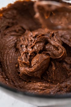 Mixing ingredients in a large glass mixing bowl to bake red velvet bundt cake with cream cheese glaze.