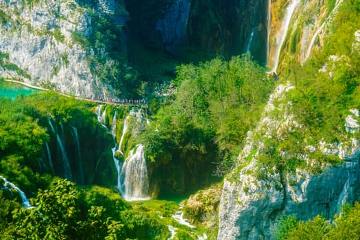 Tourists enjoy exploring the lakes and stunning landscapes in Plitvice Nature Park in Croatia during their summer holidays