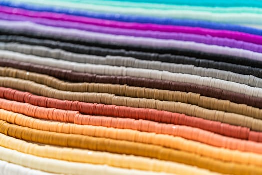 A vibrant collection of clay beads, neatly arranged by color on a white table, ready to inspire young crafters to create their own unique bracelets.