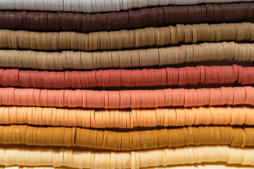 A vibrant collection of clay beads, neatly arranged by color on a white table, ready to inspire young crafters to create their own unique bracelets.