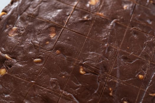 Scoring chocolate macadamia fudge using a wheel dough cutter for cutting into small square pieces.