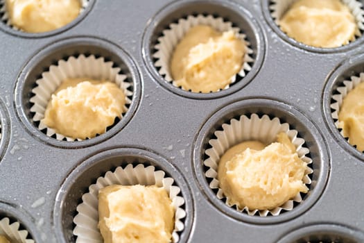 Scooping cupcake batter with dough scoop into a baking pan with liners to bake American flag mini cupcakes.