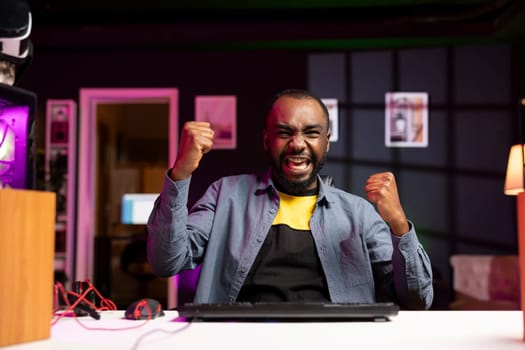 Professional gamer celebrating after winning esports online match during livestream with fans. Happy man having burst of joy after being victorious in videogame while broadcasting for audience