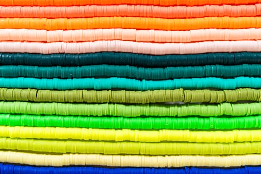 A vibrant collection of clay beads, neatly arranged by color on a white table, ready to inspire young crafters to create their own unique bracelets.