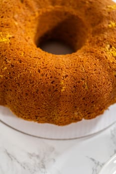 Icing the pumpkin bundt cake with cream cheese frosting and decorating it with chocolate leaves.