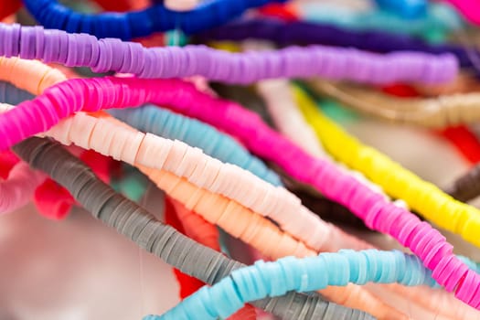 A vibrant collection of clay beads, neatly arranged by color on a white table, ready to inspire young crafters to create their own unique bracelets.