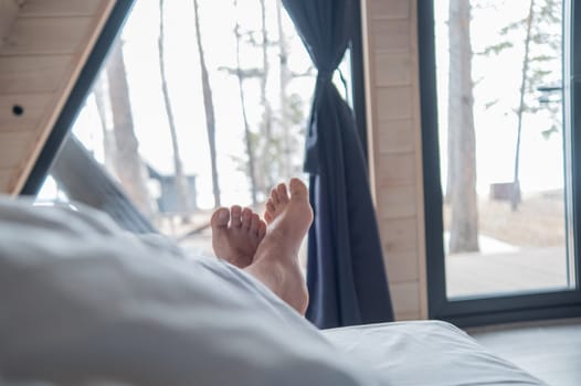 Men sticking out from under the blanket in a country house with panoramic windows