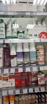 Bobruisk, Belarus - May 1, 2024: A local pharmacy display case showcasing an array of hair masks, shampoos, conditioners, balms, and sun creams on a well-lit morning.