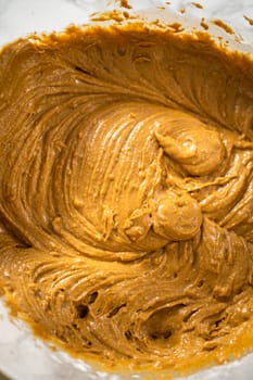 Mixing ingredients in a large glass mixing bowl to bake gingerbread cupcakes.